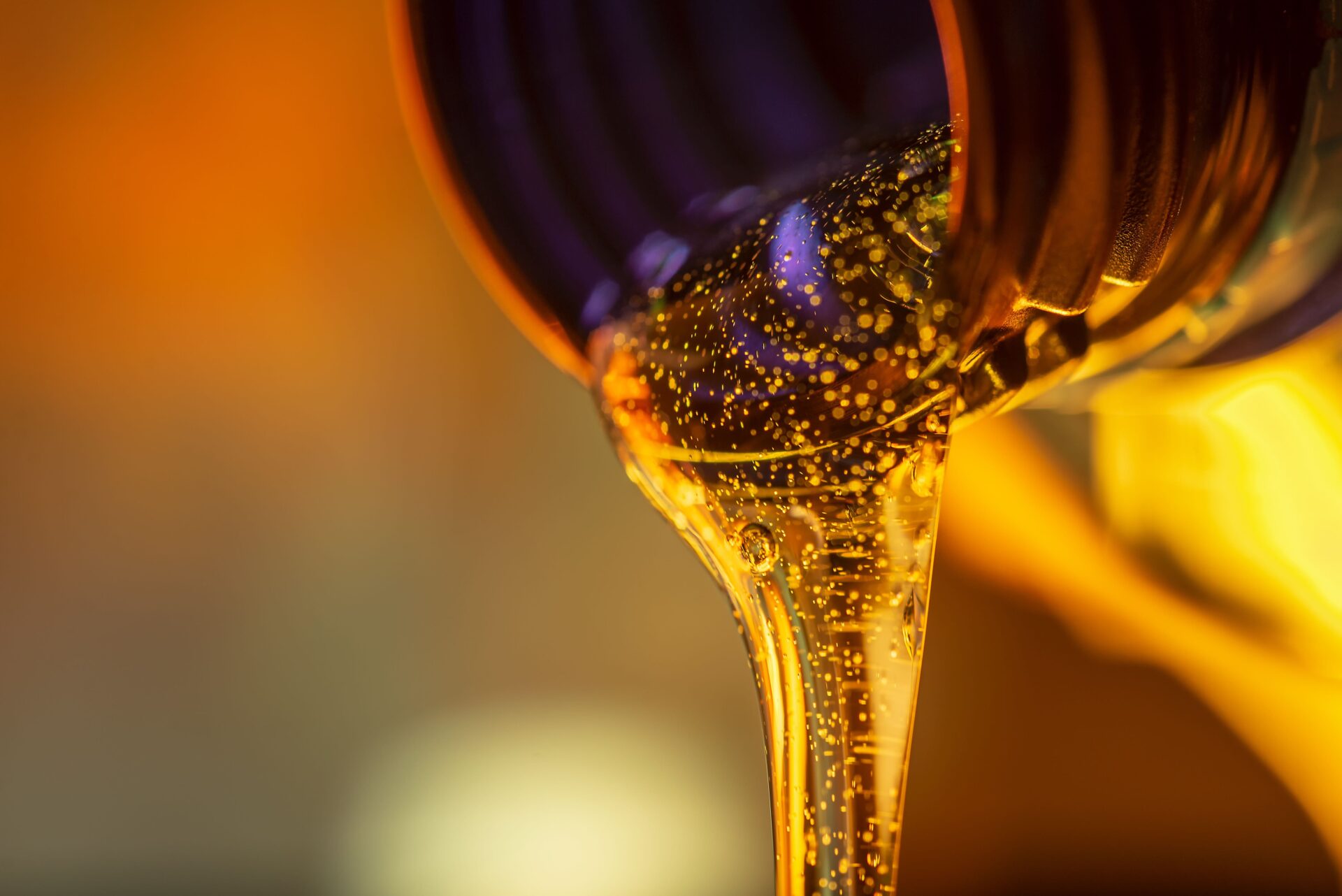 Liquid stream of motorcycle motor oil flows from the neck of the bottle close-up. LUBRICANTS Winkler, MB